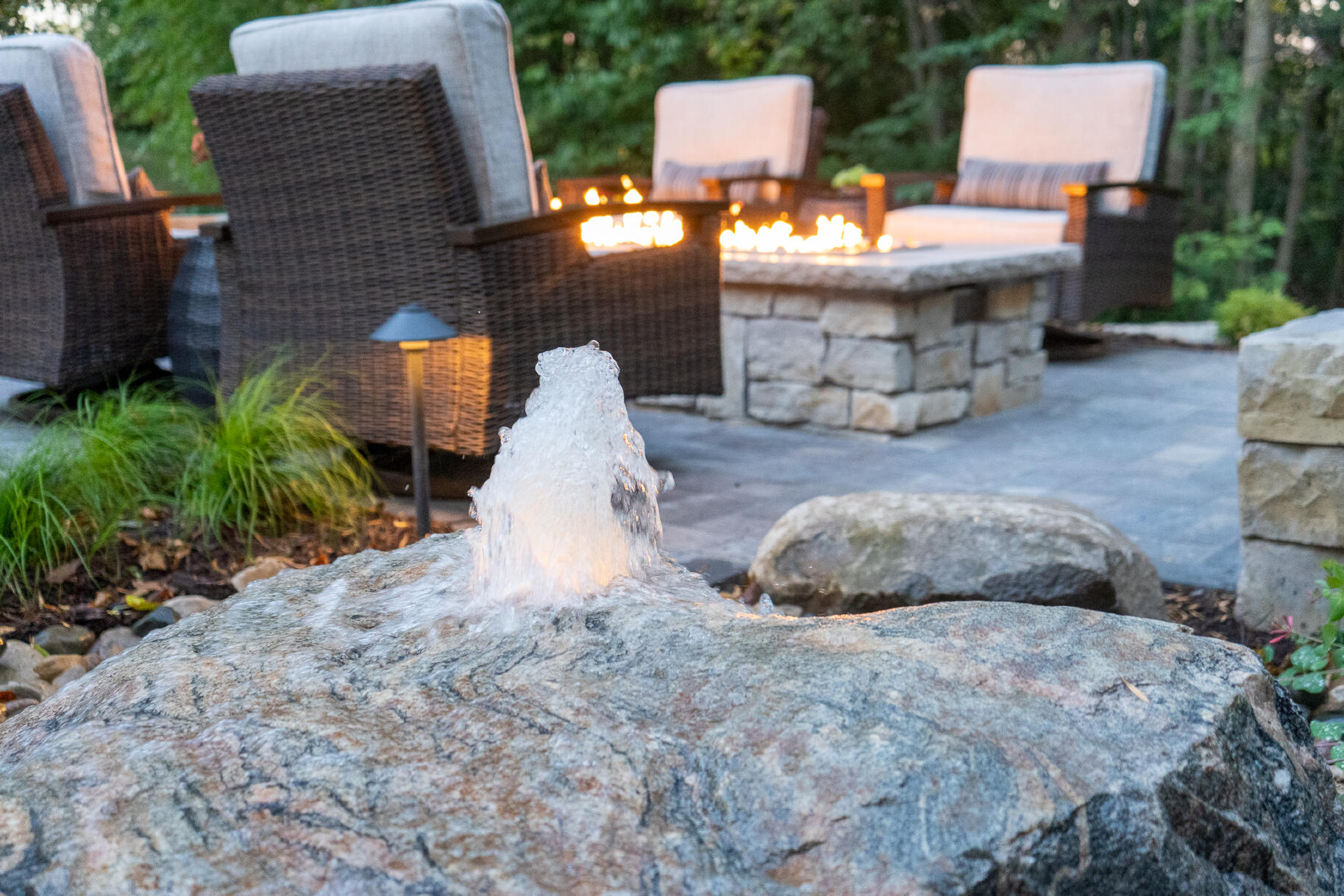 Outdoor paver patio with seating, oblong fire ring and waterfall feature